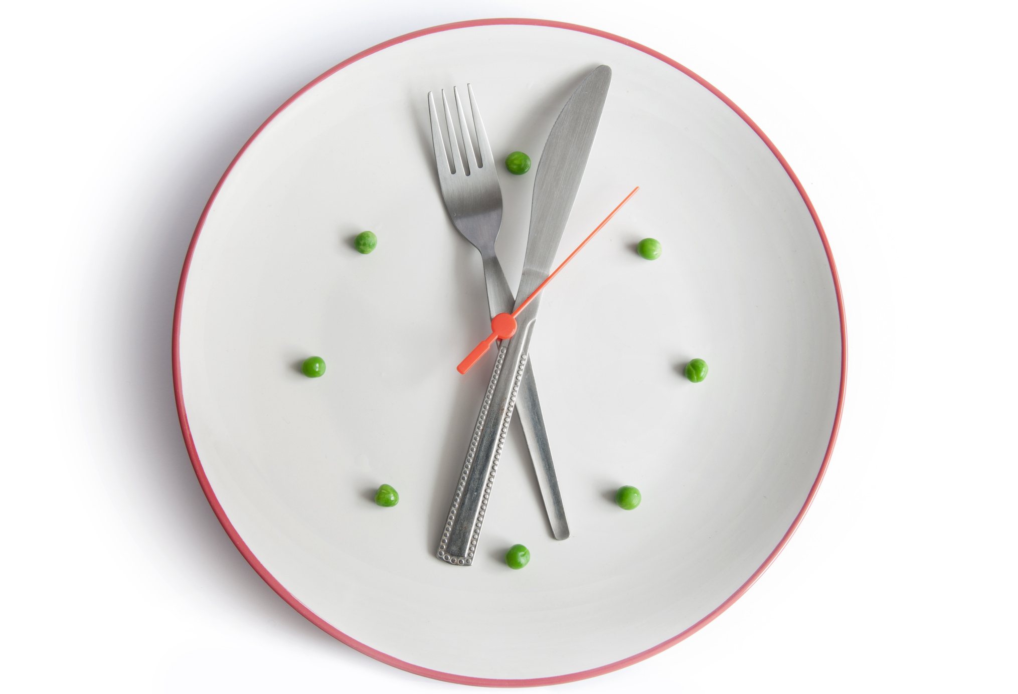 A plate with a fork and knife set like clock hands, with peas marking the hours